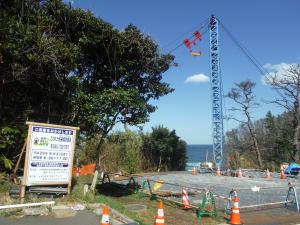 船尻地区農地海岸復旧工事の工事看板（右側）と、、ケーブルクレーン（左側）の写真