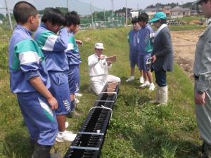 「水田魚道」の装置＆作業手順を説明する講師役男性、及び大谷中学校の生徒たち