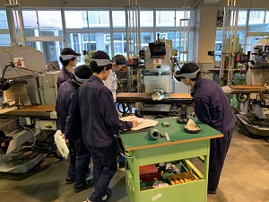 フライス盤の指導を受けている学生の様子
